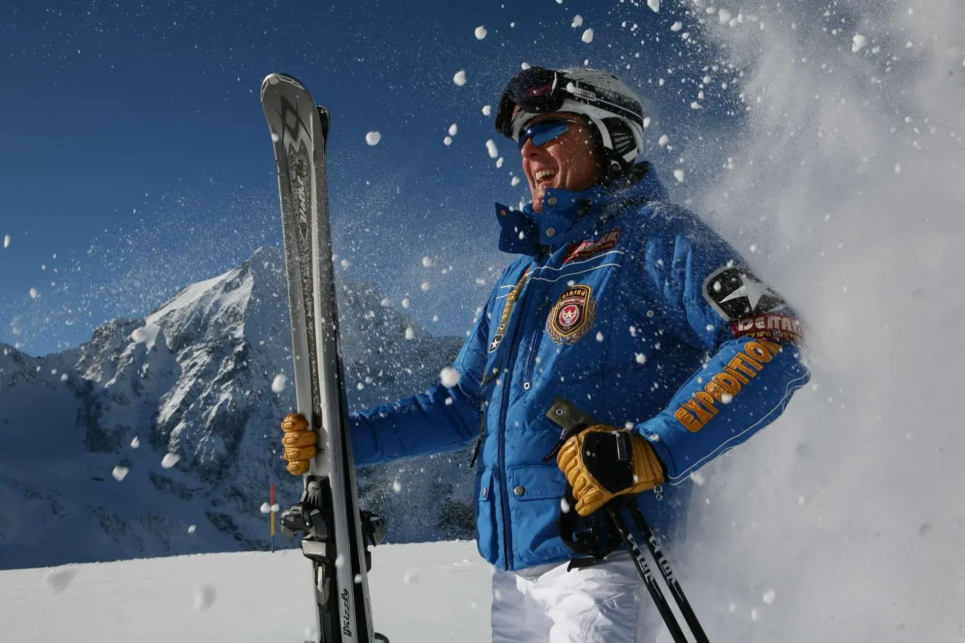 Skifahrer im aufstiebenden Pulverschnee vor den Gipfeln