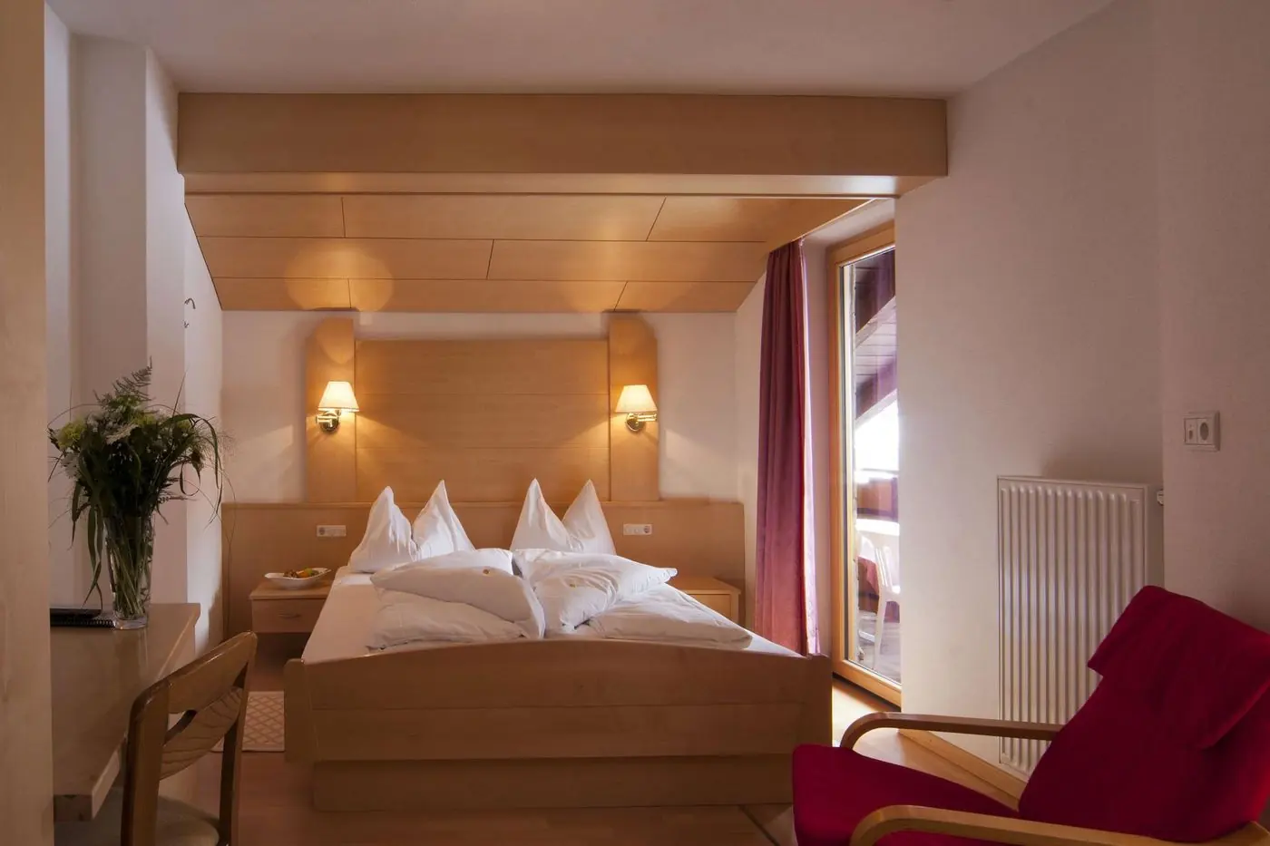 Klassisches Doppelzimmer mit hellem Holz und rotem Sessel